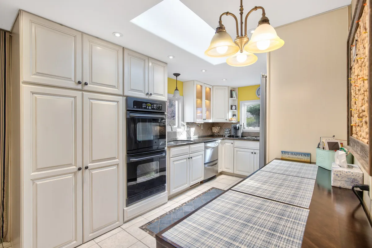 A functional and welcoming kitchen with wood cabinetry, a central island with bench seating, and a prominent skylight. Modern appliances are visible, suggesting the kitchen is well-stocked and ready for culinary adventures or morning coffee rituals.